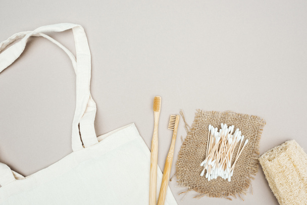 fa fogkefék, szerves luffa, vattatampon, zsákkendővel és fehér pamut táska szürke háttérrel - Fotó, kép