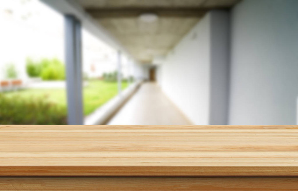 Holzbraune Tischplatte vor dem verschwommenen Flur, Durchgang und Innenhof des Hauses. Für die Produktpräsentation ist Montage oder Design das Schlüsselbild des Layouts. - Foto, Bild