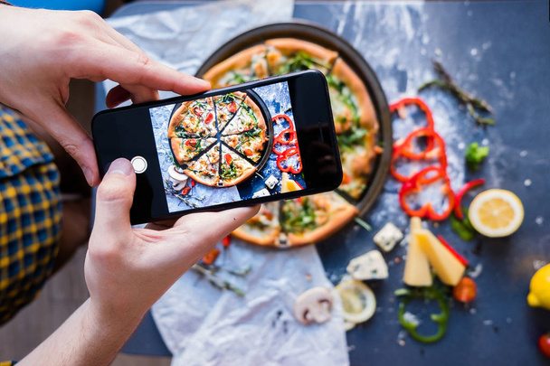 Man taking photo of pizza with smartphone Closeup view of process - Fotó, kép