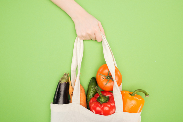 vista recortada de la mujer que sostiene la manija de la bolsa de algodón llena de verduras maduras
 - Foto, Imagen