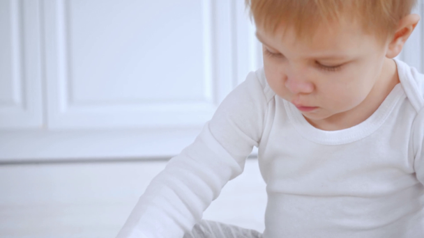 selektiver Fokus des entzückenden Kleinkindes, das auf Teppich sitzt und mit bunten Holzklötzen spielt - Filmmaterial, Video