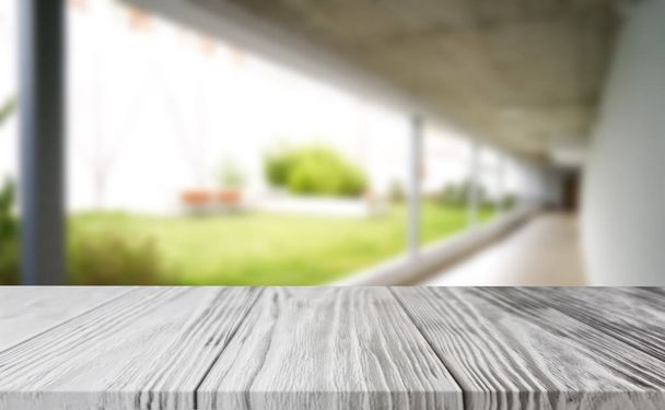 Wooden brown table top against the blurred corridor, passage and courtyard of the house .For product display montage or design is the key visual of the layout. - Photo, Image