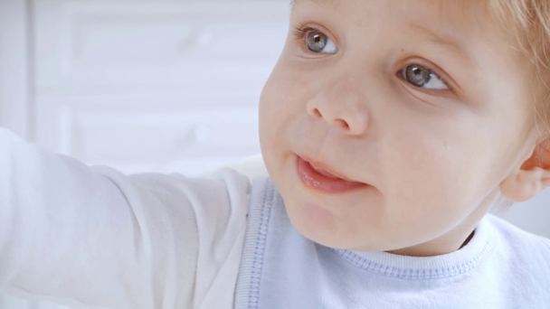 entzückender Kleinkind-Junge in Latz isst leckeres Püree aus Plastikgeschirr - Filmmaterial, Video