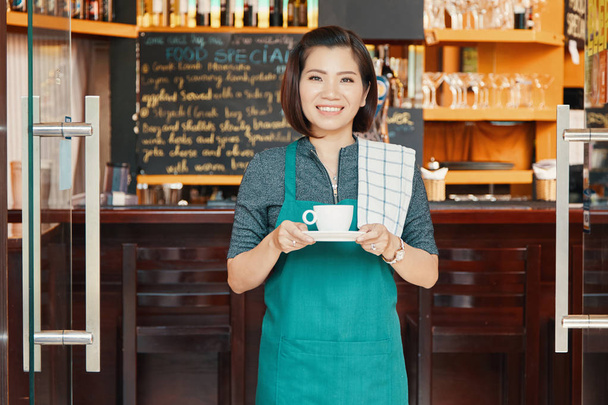 Bastante camarera vietnamita ofreciendo una taza de café
  - Foto, Imagen