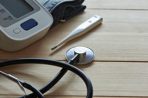Stetoscopio, sfigmomanometro e termometro su dorso in legno
 - Foto, immagini