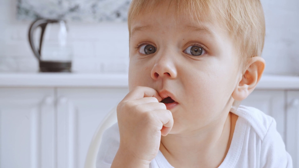 Lustiger Kleinkind-Junge, der sich die Nase zupft, dann Mutter wischt und Sohn zeigt mit dem Finger in die Kamera - Filmmaterial, Video