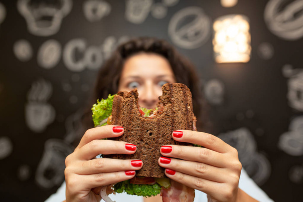 Zabawny zbliżenie niewyraźne protrait z młoda kobieta trzymać ugryziony sandwi - Zdjęcie, obraz
