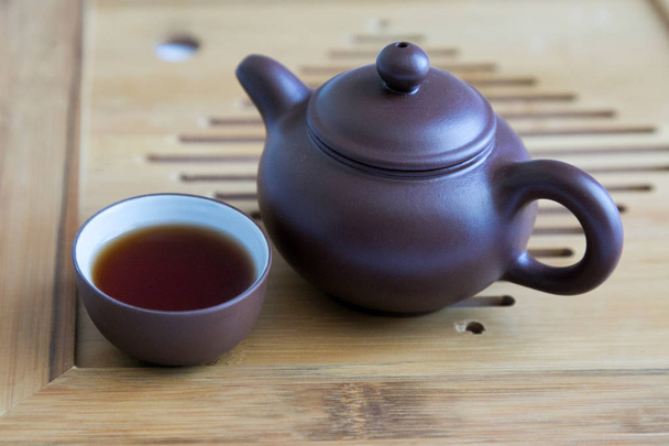 Miniature antique tableware for tea on a wooden tray. Teapot and cup made of clay on a wooden background - Foto, imagen