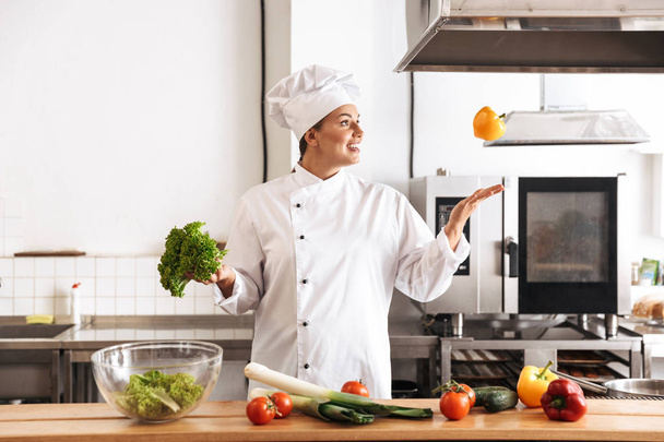 Photo of positive woman chef wearing white uniform cooking meal  - Fotó, kép