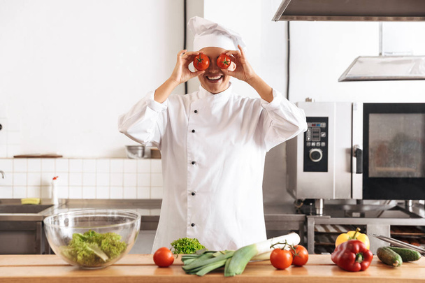 Photo of cheerful woman chef wearing white uniform cooking meal  - Foto, imagen