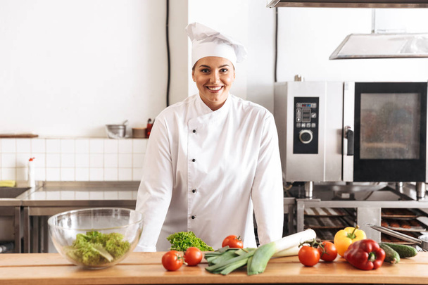 Photo of adult woman chef wearing white uniform cooking meal wit - Фото, зображення