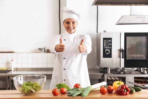 Photo of joyful woman chef wearing white uniform cooking meal wi - Foto, immagini