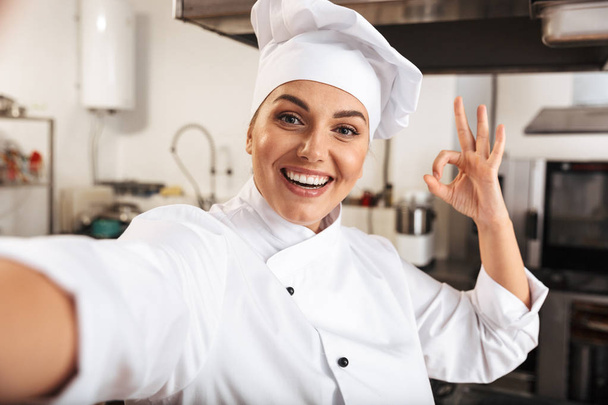 Portrait of beautiful woman chef wearing white uniform, taking s - 写真・画像