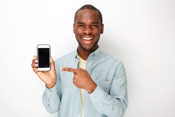 Portret szczęśliwego młodego afrykańskiego amerykańskiego mężczyznę trzymującego telefon komórkowy i wskazujący ekran - Zdjęcie, obraz