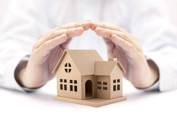 Property insurance. House miniature covered by hands.  - Zdjęcie, obraz