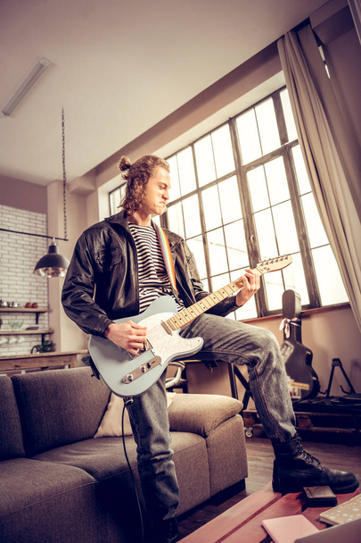 Musician with hair bun getting much satisfaction playing rock music - 写真・画像