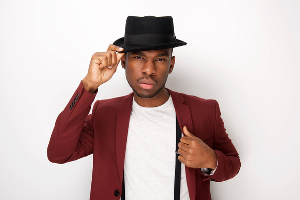 Portrait of cool african male fashion model posing with hat and blazer by white background - Photo, image