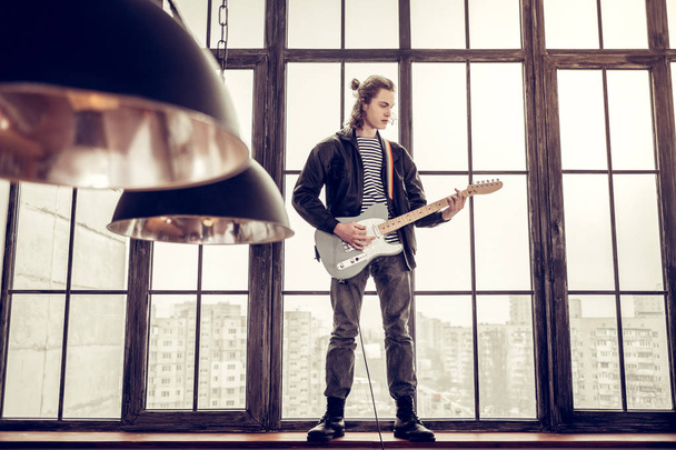 Rock musician standing on window sill and playing the guitar - Φωτογραφία, εικόνα