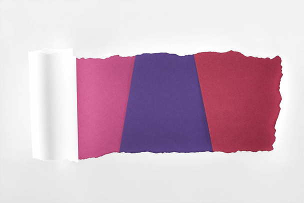 zerrissenes texturiertes weißes Papier mit gerolltem Rand auf farbigem Hintergrund  - Foto, Bild