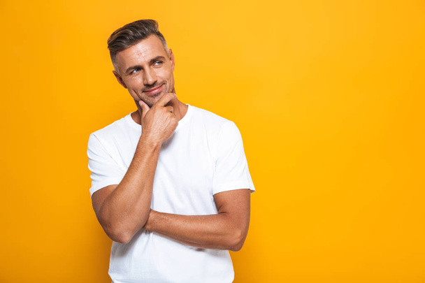 Handsome serious man posing isolated over yellow wall background. - Foto, afbeelding