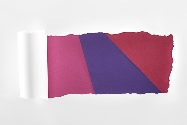 ragged textured white paper with rolled edge on colored background  - Fotó, kép
