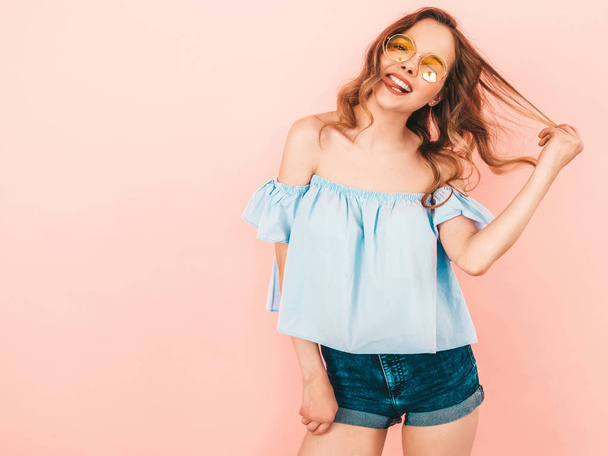 Portrait of beautiful smiling cute model in round sunglasses. Girl in summer hipster colorful clothes. Model posing on pink  background - Foto, Imagem