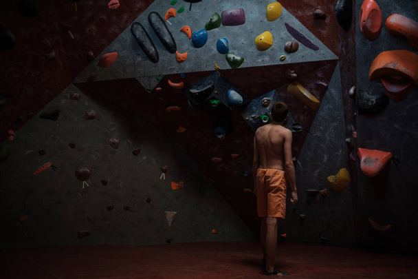 Athletic man practicing in a bouldering gym - Фото, изображение