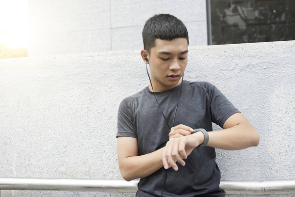 Młoda Azji człowiek sprawdzanie zegarek fitness kroków, zrobił na jego fitness tracker - Zdjęcie, obraz