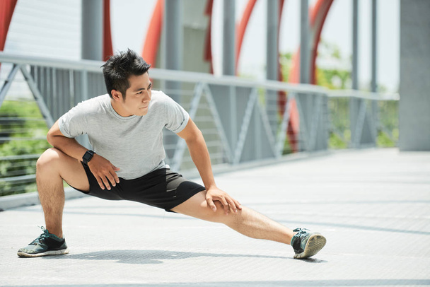 спортивный азиат, растягивающий ноги
  - Фото, изображение