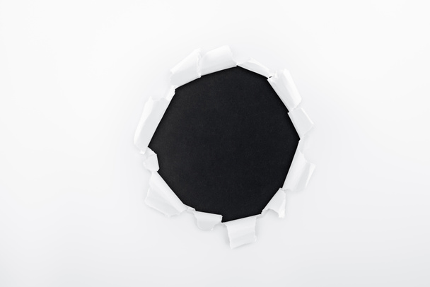 ragged hole in textured white paper on black background  - Foto, Bild