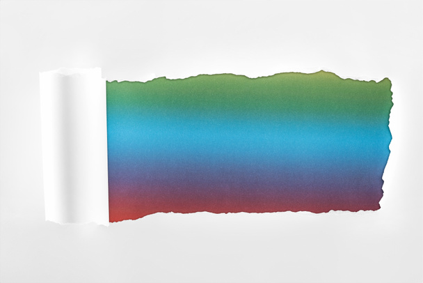 papel blanco rasgado con borde laminado sobre fondo multicolor
  - Foto, imagen
