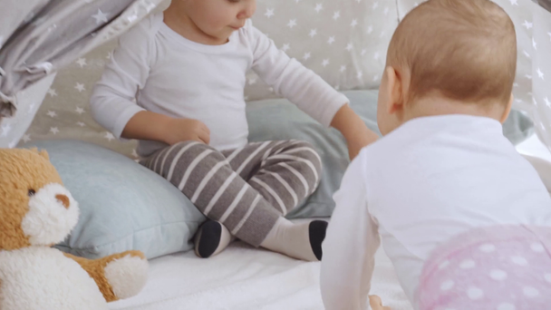 chłopiec uśmiechnięty maluch siedzi w Baby Wigwam podczas gdy mała siostra indeksowania na czworakach  - Materiał filmowy, wideo