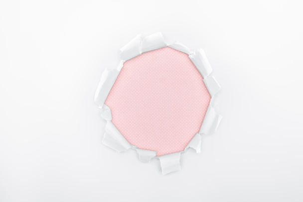 ragged hole in textured white paper on pink background  - Foto, Imagem
