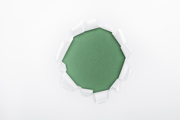ragged hole in textured white paper on green background  - Foto, imagen
