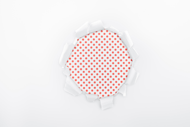 roztrhaný otvor v bílém papíře s texturou na červené polkové pozadí  - Fotografie, Obrázek