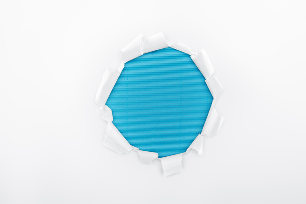 roztržený otvor v bílém texturovaném papíře na modrém proužkované pozadí  - Fotografie, Obrázek