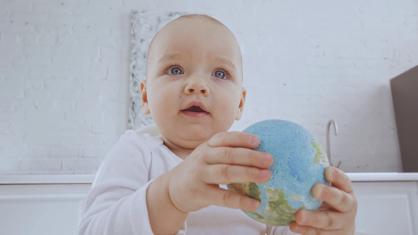 ハイチェアに座っておもちゃの地球儀で遊んでかわいい子供を笑顔 - 映像、動画