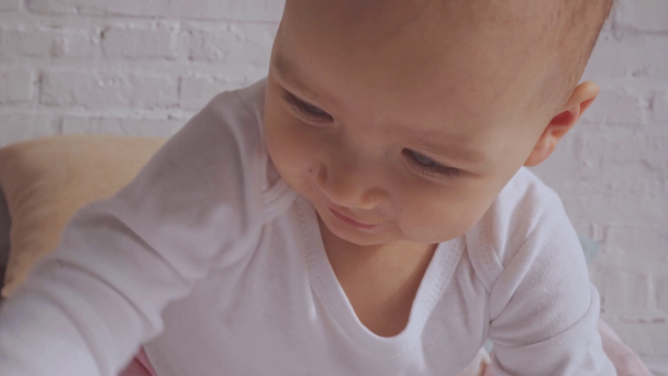 cute smiling child taking off pink headband while sitting on bed - Imágenes, Vídeo
