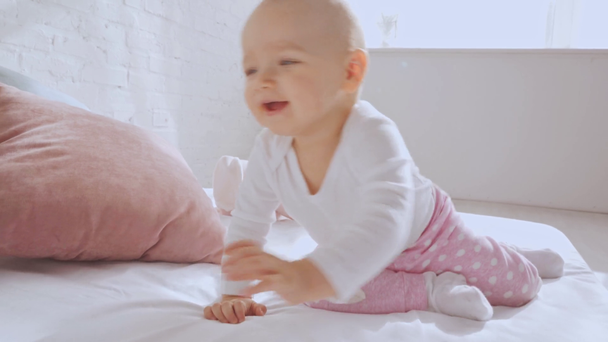 adorable happy toddler child sitting on bed and playing with pillows and mother - Footage, Video