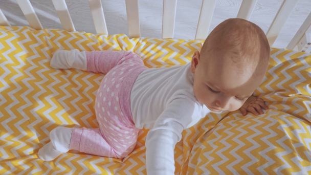  hymyilevä lapsi makaa vauvansängyssä leikkiessään äidin kanssa ja sitten nousee ja katselee ympärilleen
 - Materiaali, video