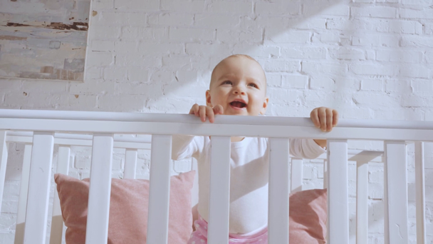 adorable smiling toddler child in baby crib throwing toy  - Záběry, video