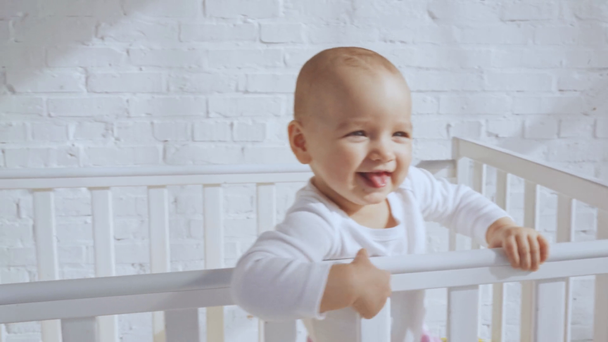 Niedliche Kind in Babybett zeigt mit dem Finger und dann Mutter gibt Tochter Spielzeug Kaninchen  - Filmmaterial, Video