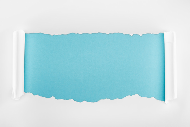 σχισμένο λευκό χαρτί με καμπυλωση ακμές σε ανοιχτό μπλε φόντο  - Φωτογραφία, εικόνα