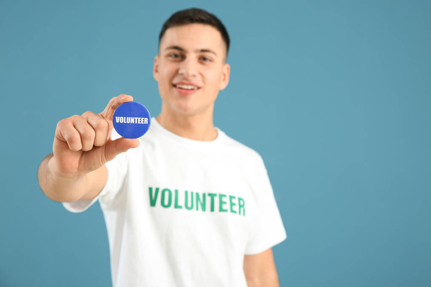Молодой волонтер со значком на цветном фоне
 - Фото, изображение