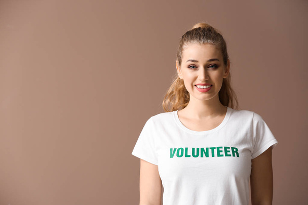 Young female volunteer on color background - Foto, Bild