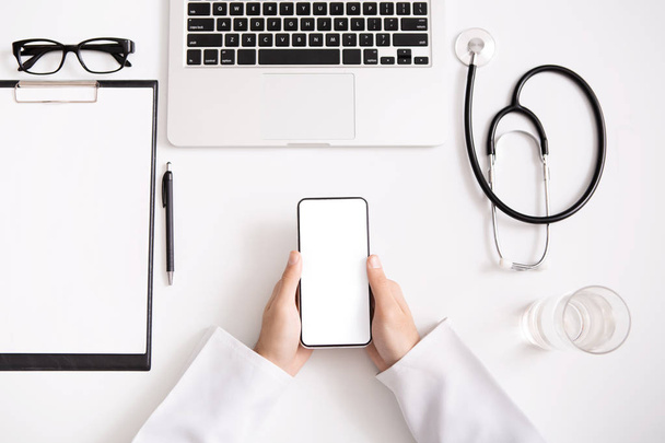 Médico usando smartphone com tela em branco no local de trabalho
 - Foto, Imagem