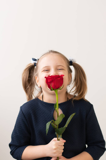 little girl stands with a red rose - Фото, зображення