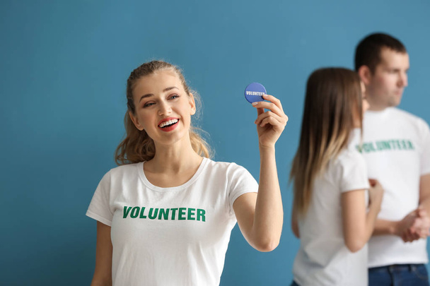 Young female volunteer and her team on color background - Photo, Image