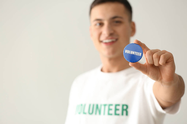 Fiatal férfi önkéntes jelvény-ra könnyű háttér - Fotó, kép