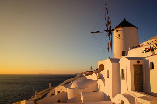 夕日の穏やかな黄色は中世の小型風車は、ロマンチックなサントリーニ島の主なアトラクションです。ギリシャ. - 写真・画像